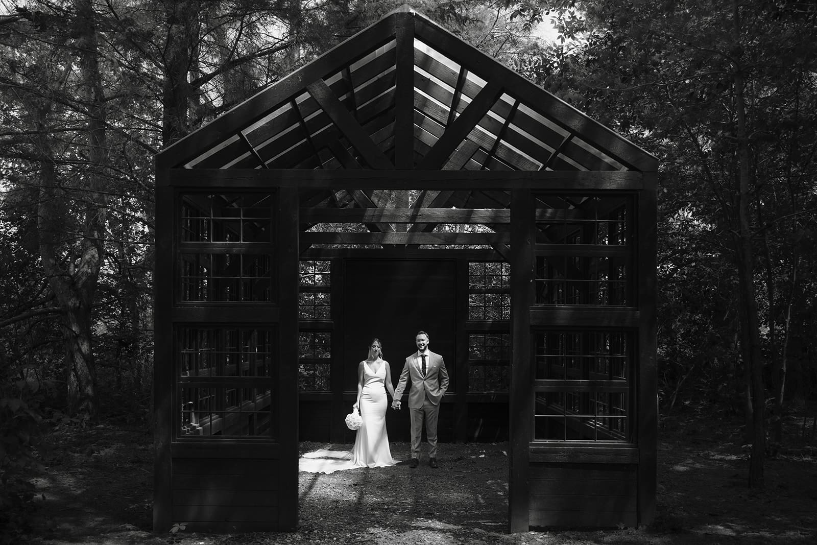 Bride and groom portraits under modern black structure in the woods at Ivory North wedding venue in Minnesota. 