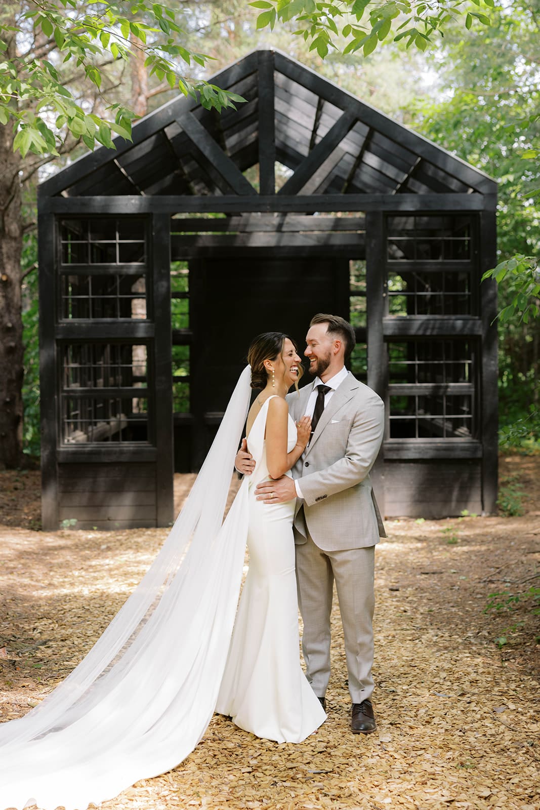Bride and groom portraits under modern black structure in the woods at Ivory North wedding venue in Minnesota. 