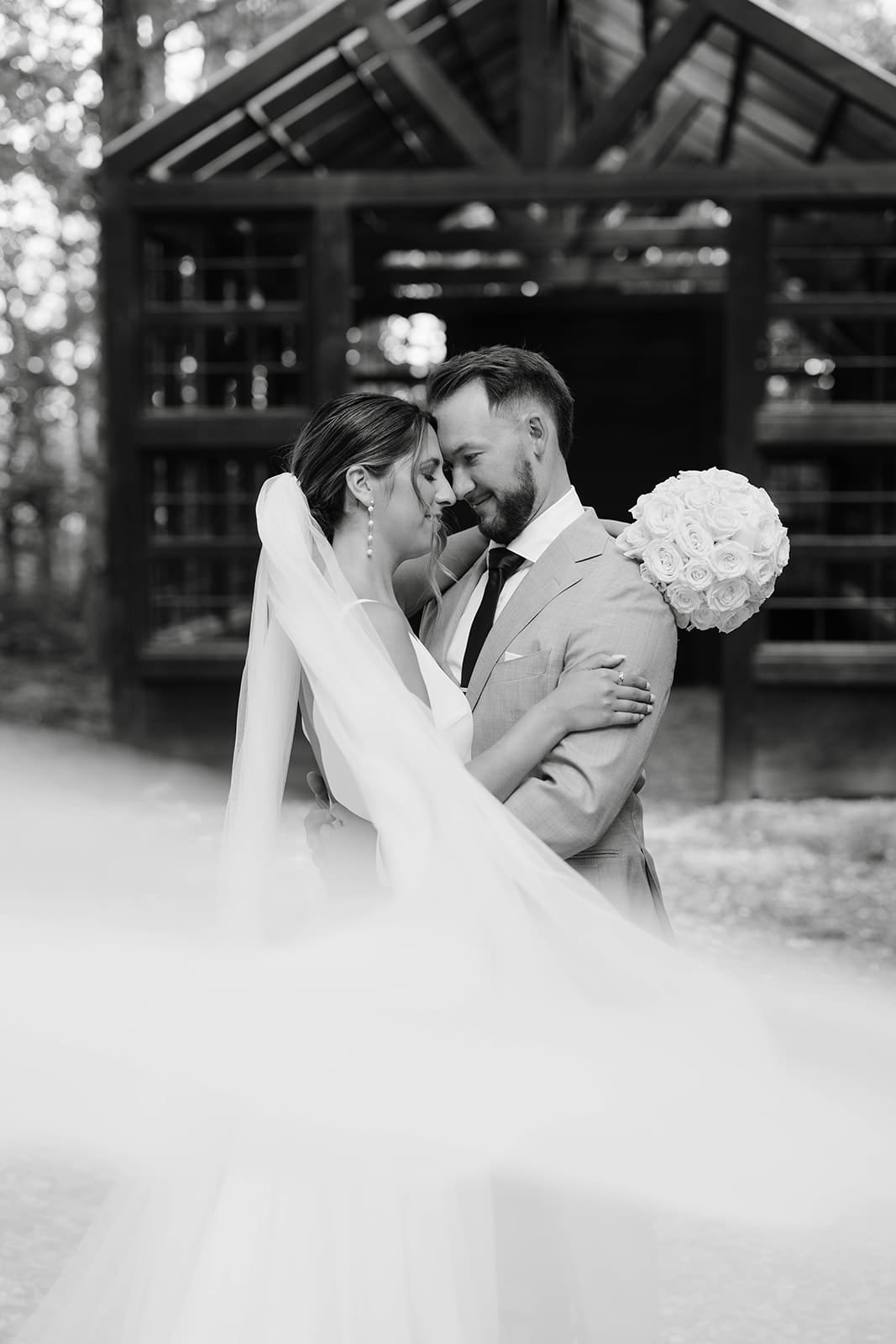 Bride and groom portraits under modern black structure in the woods at Ivory North wedding venue in Minnesota. 