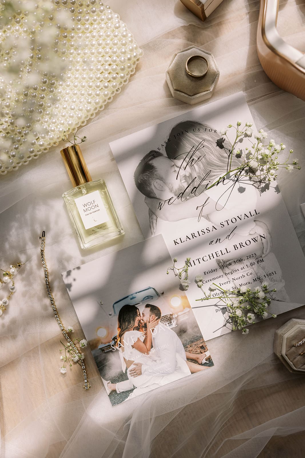 Bridal details flat lay photo of the wedding invite, jewelry, bag, and veil. 