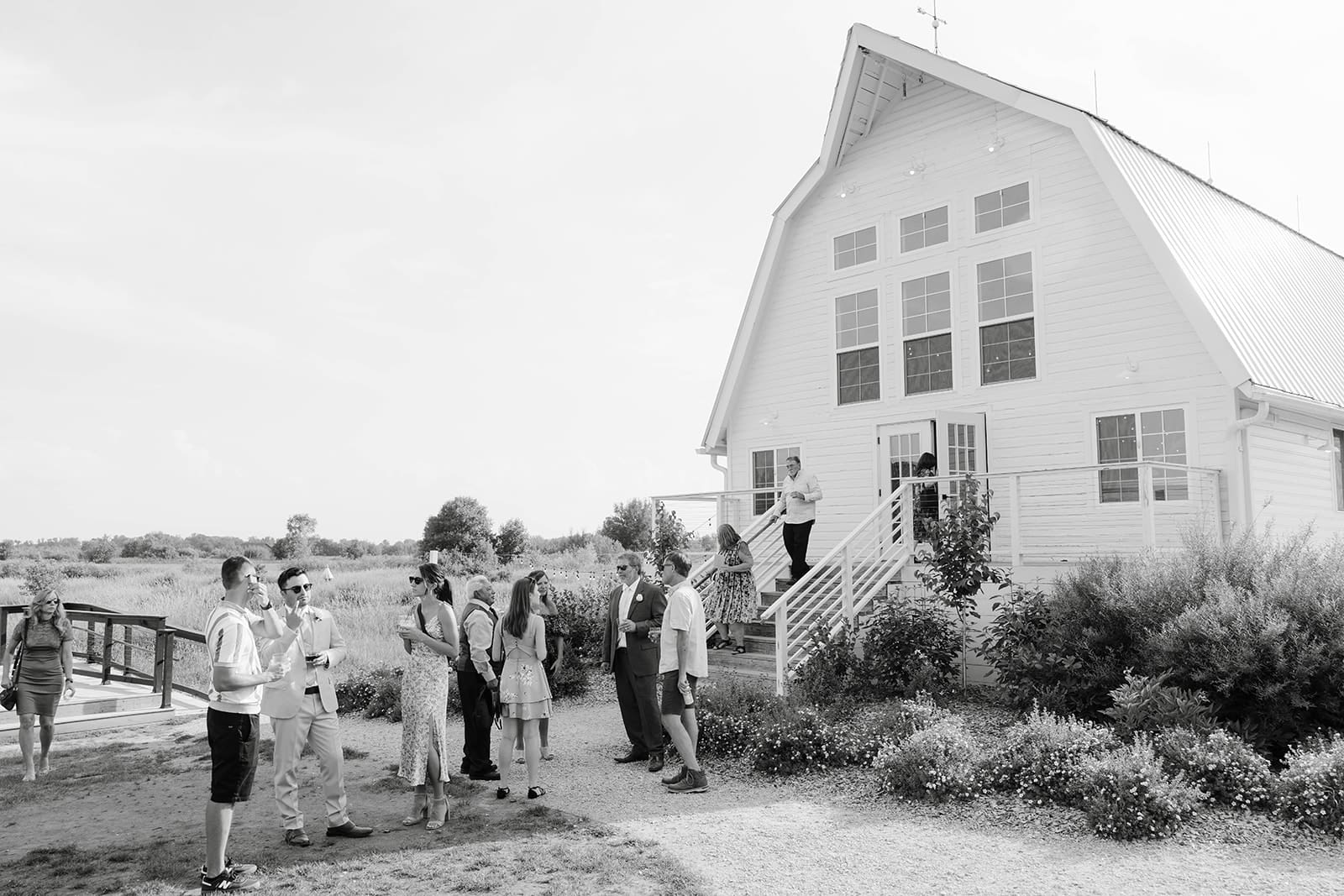 Guests on the lawn posing with the white barn wedding venue at ivory North in Mora, MN. 