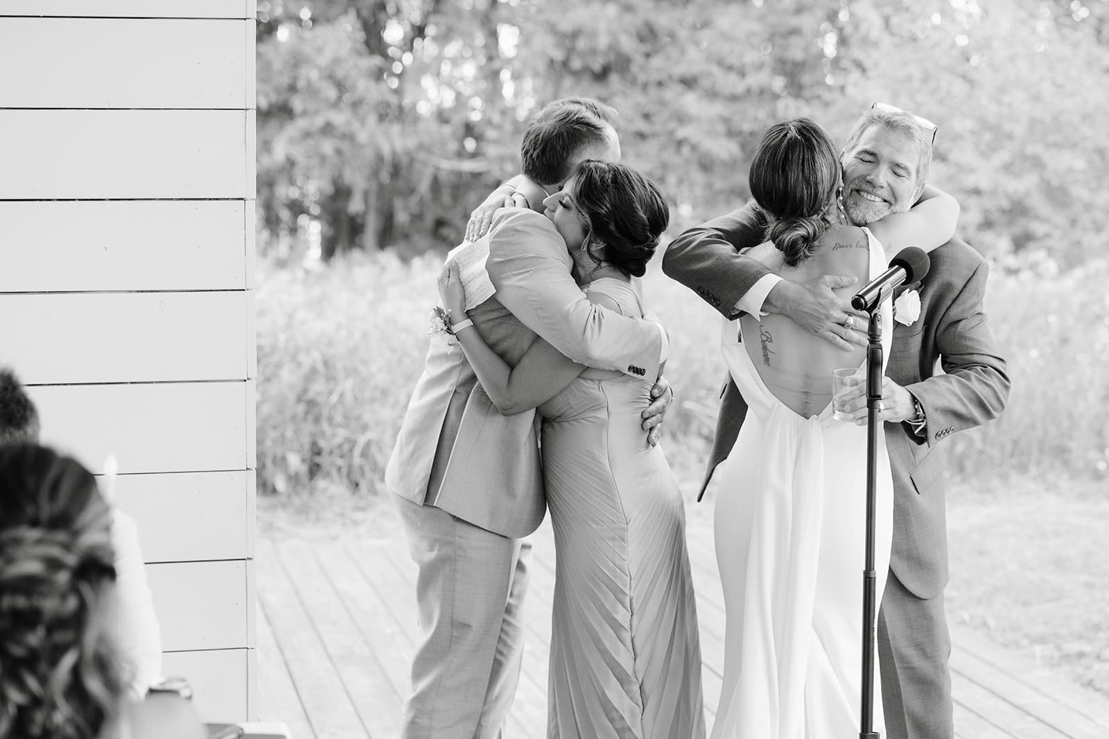 Bride and groom hugging parents during wedding reception speeches at a central Minnesota wedding. 