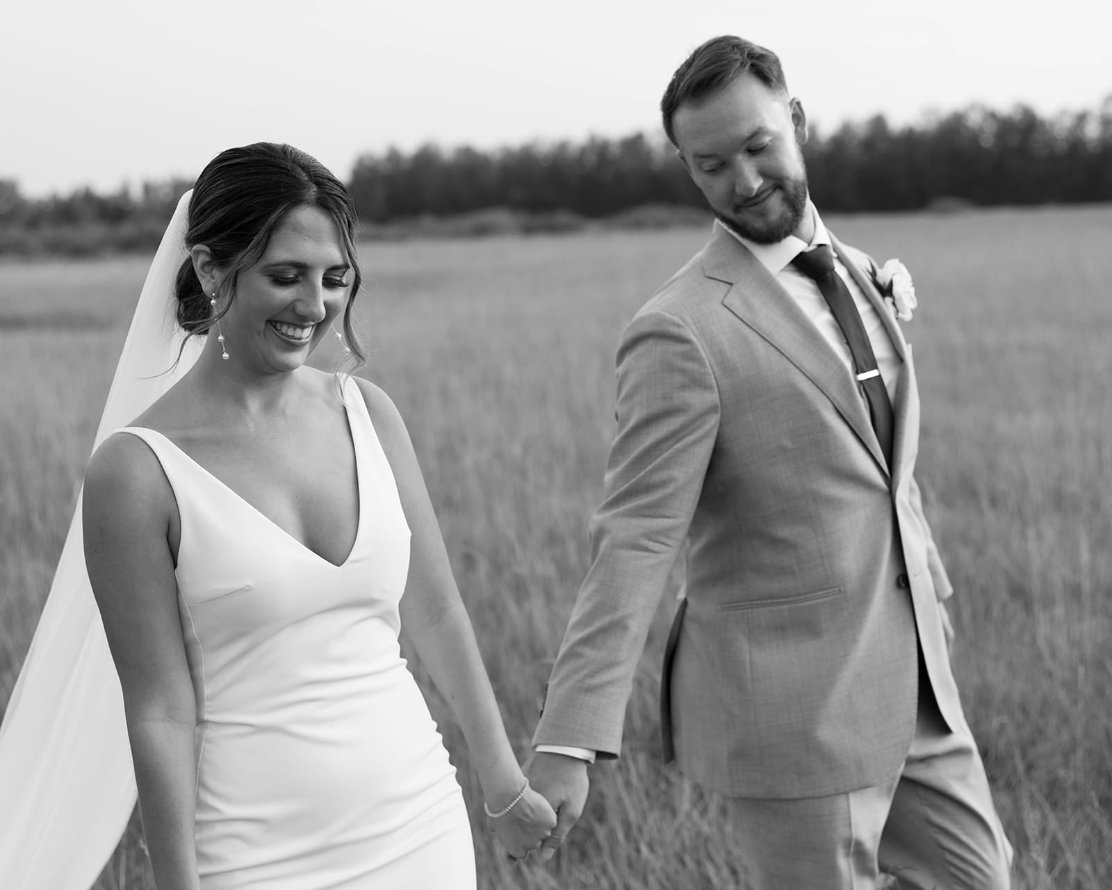 Bride and groom photo walking through the grassy field at Ivory North Co in Mora, MN.