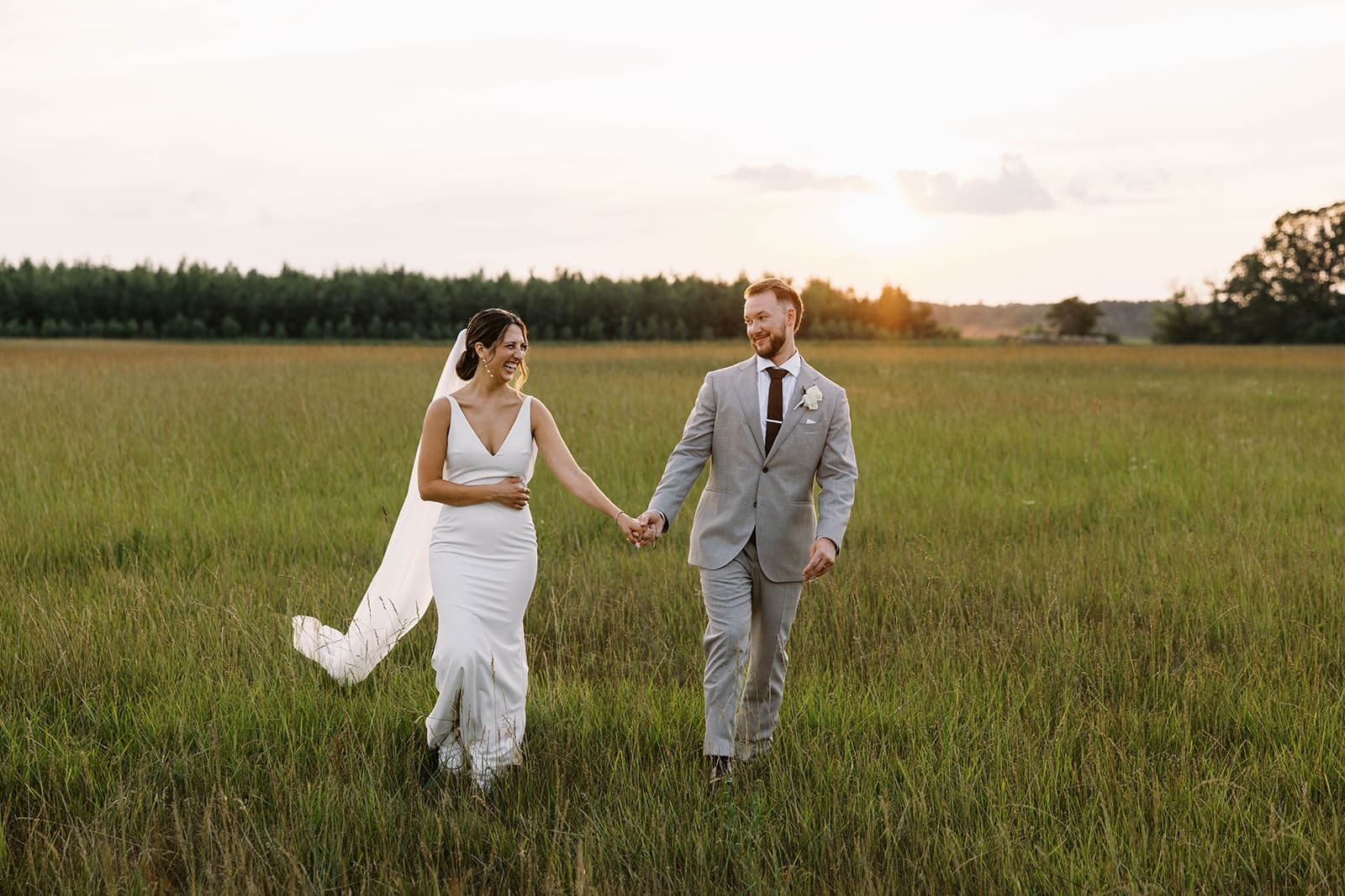 Bride and groom photo walking through the grassy field at Ivory North Co in Mora, MN.