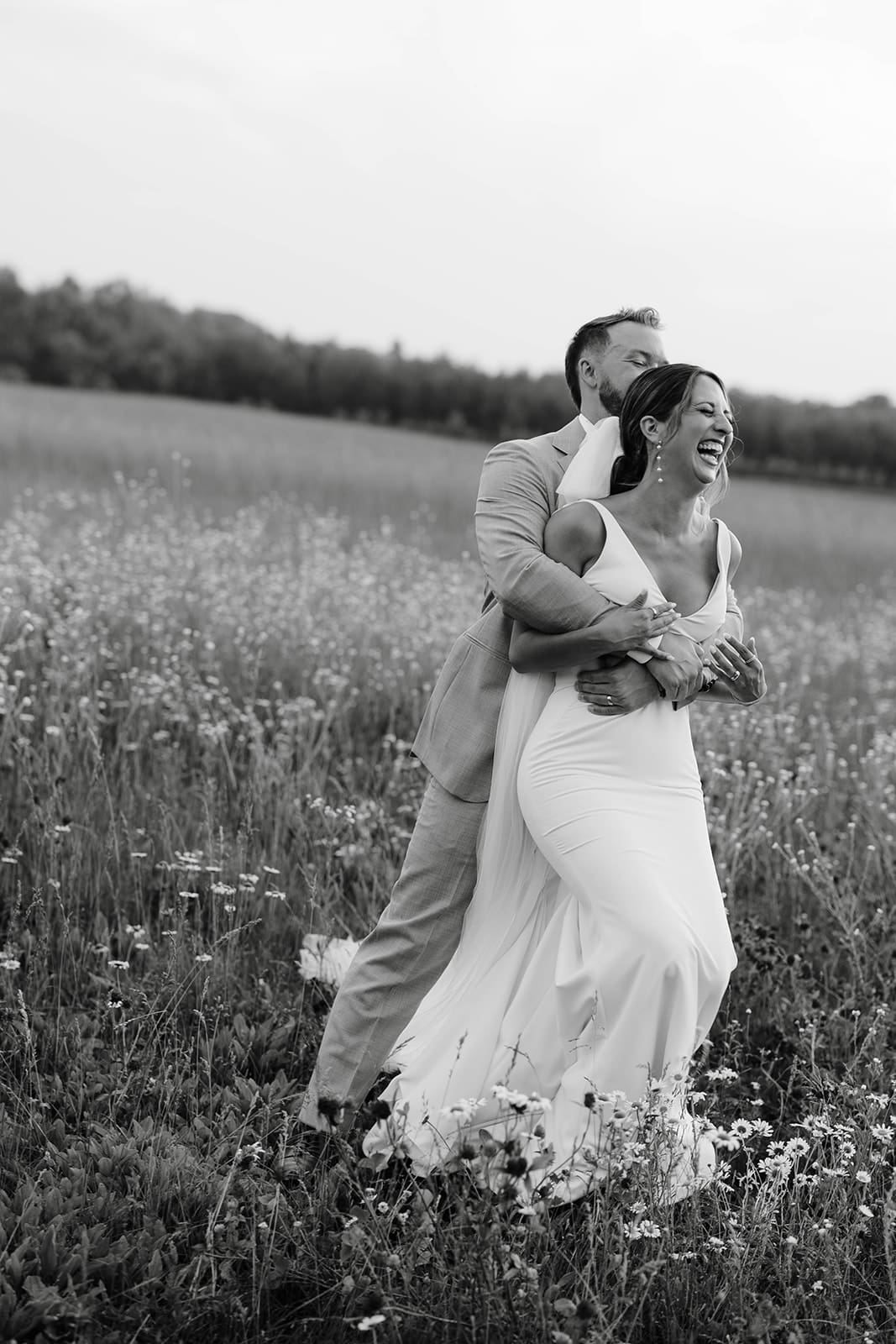 Bride and groom laughing portraits in the flower meadow at Ivory North wedding venue in Mora, MN.