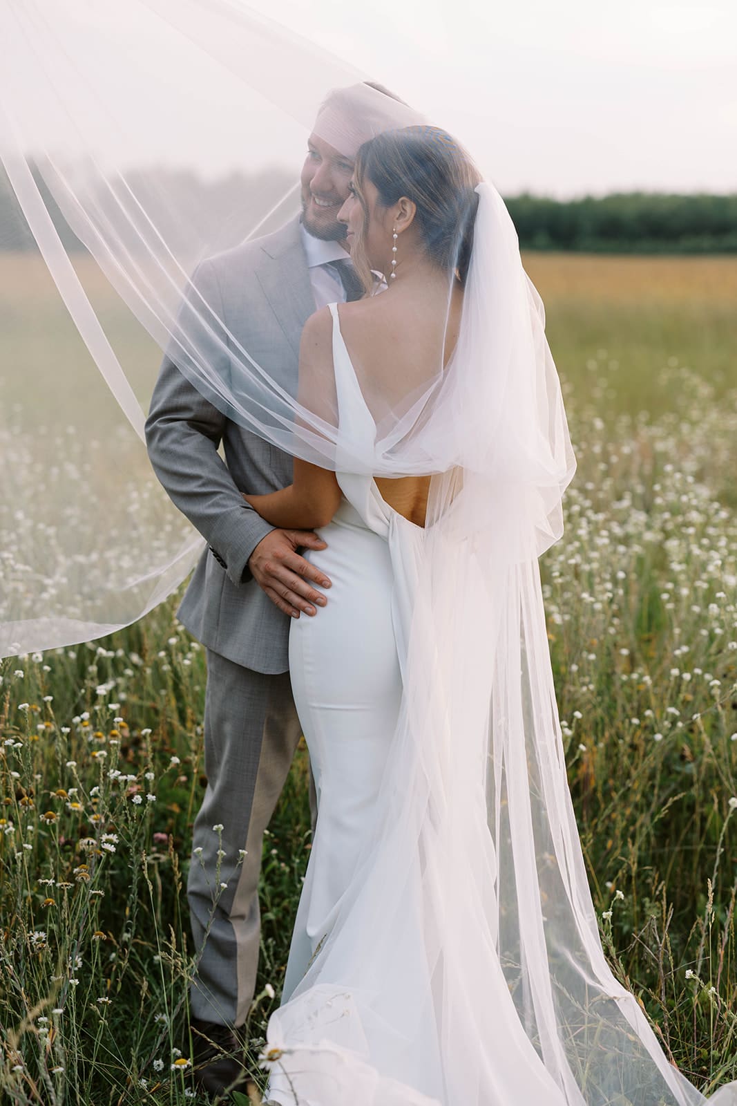 Bride and groom veil portraits in the flower meadow at Ivory North wedding venue in Mora, MN.