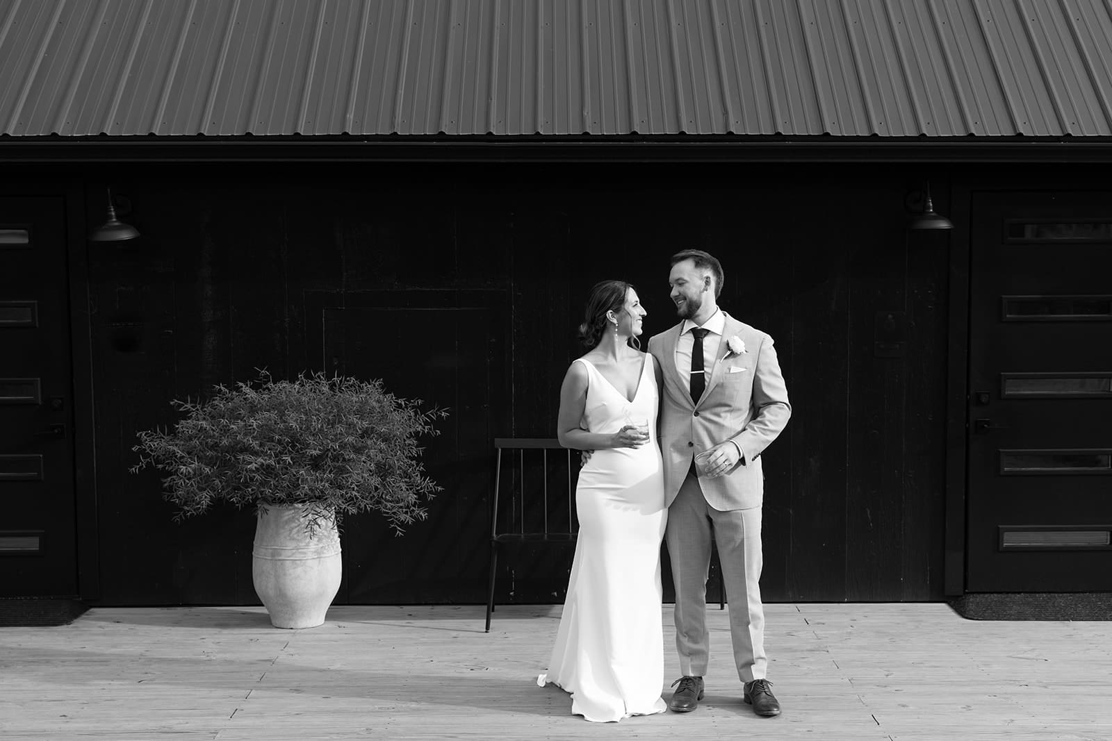 Bride and groom posing for a photo during cocktail hour on a black background at Ivory North wedding venue by Tom Thornton Photography. 