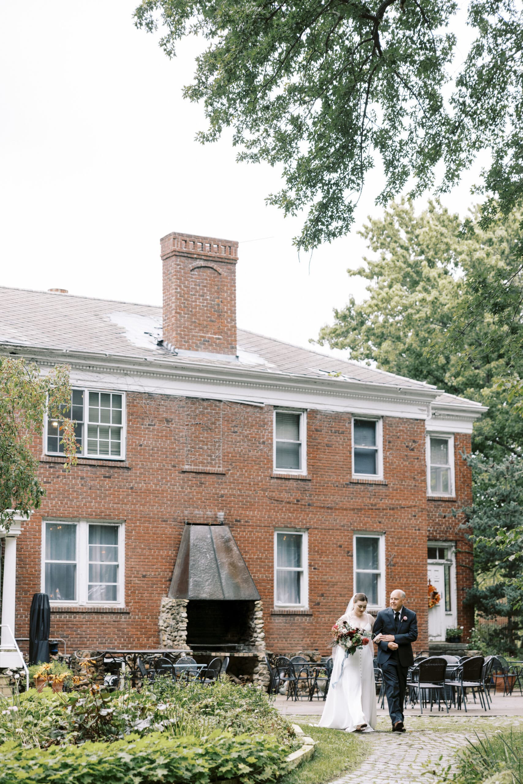Bride walking down the aisle with Dad to the garden for their outing lodge wedding ceremony. 