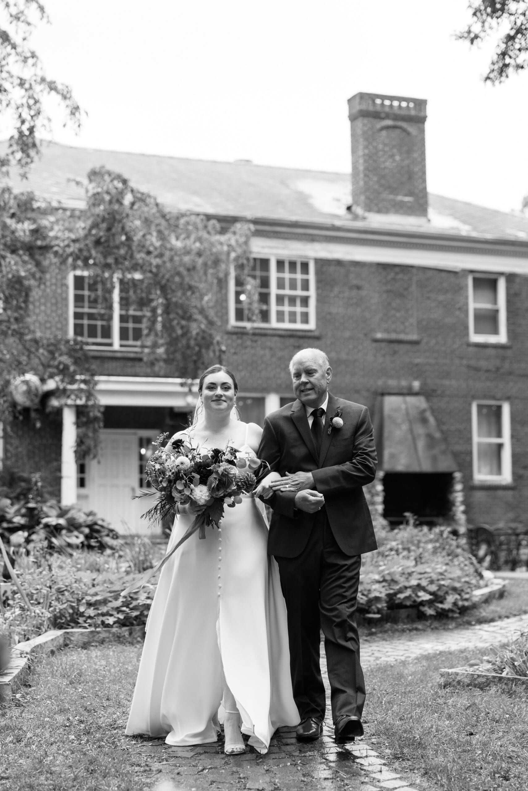 Bride walking down the aisle with Dad to the garden for their outing lodge wedding ceremony. 