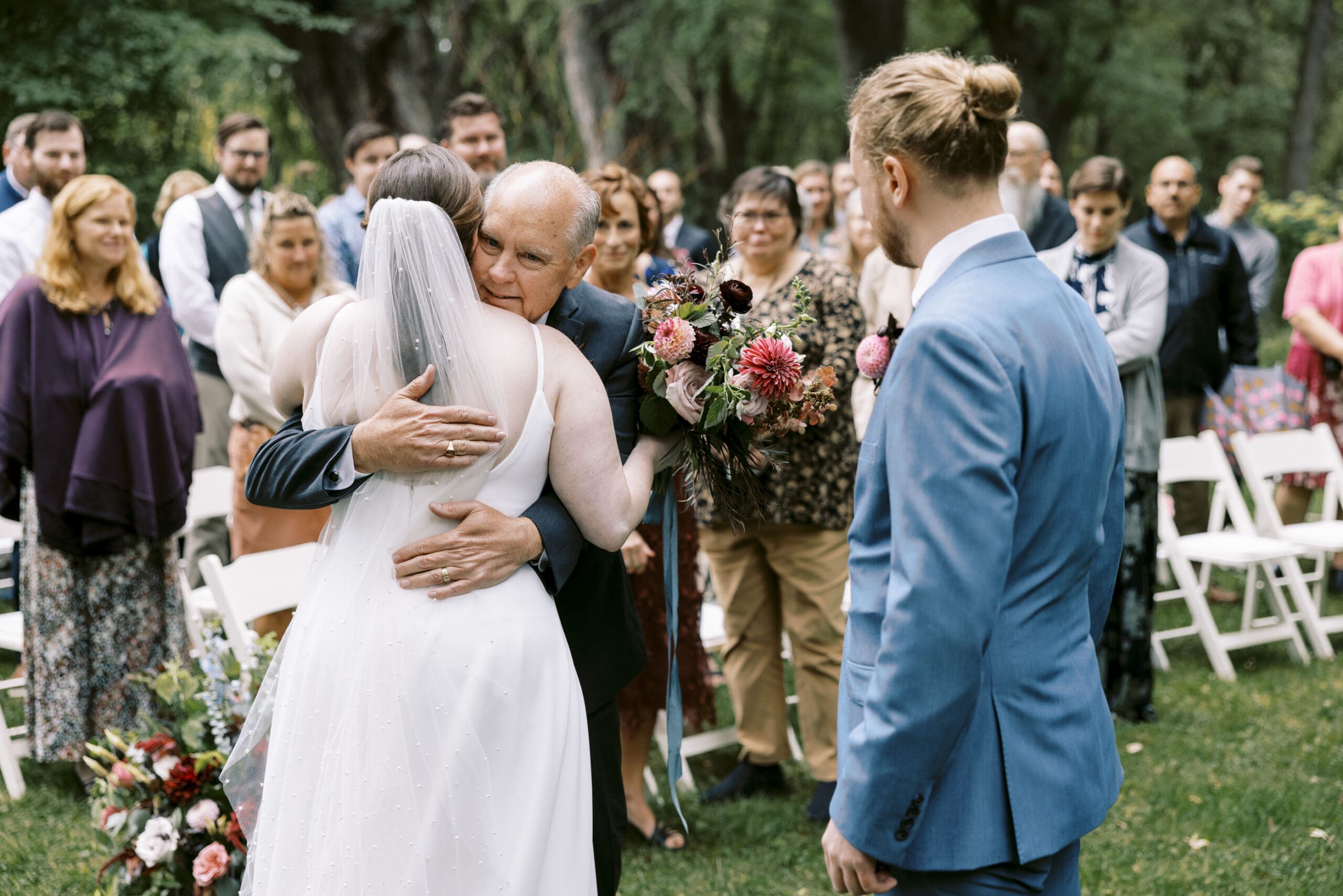 Bride's dad hugging her after walking her down the aisle at this stillwater wedding at the outing lodge.