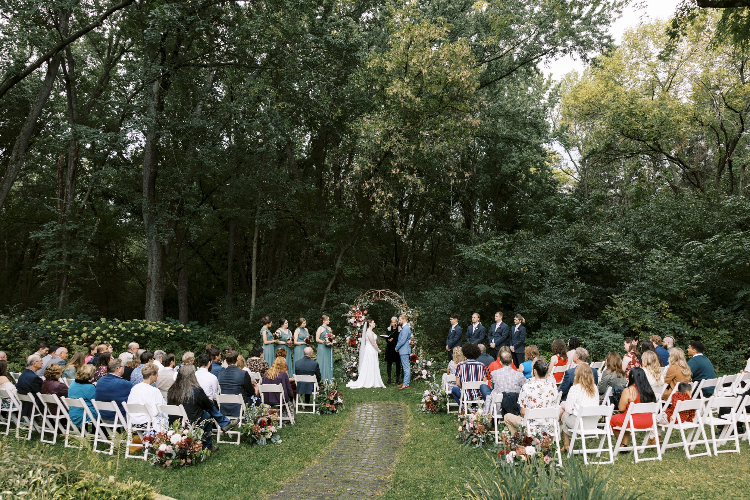 Wide photo of the entire wedding ceremony in the garden at the outing lodge in Stillwater, Minnesota. 