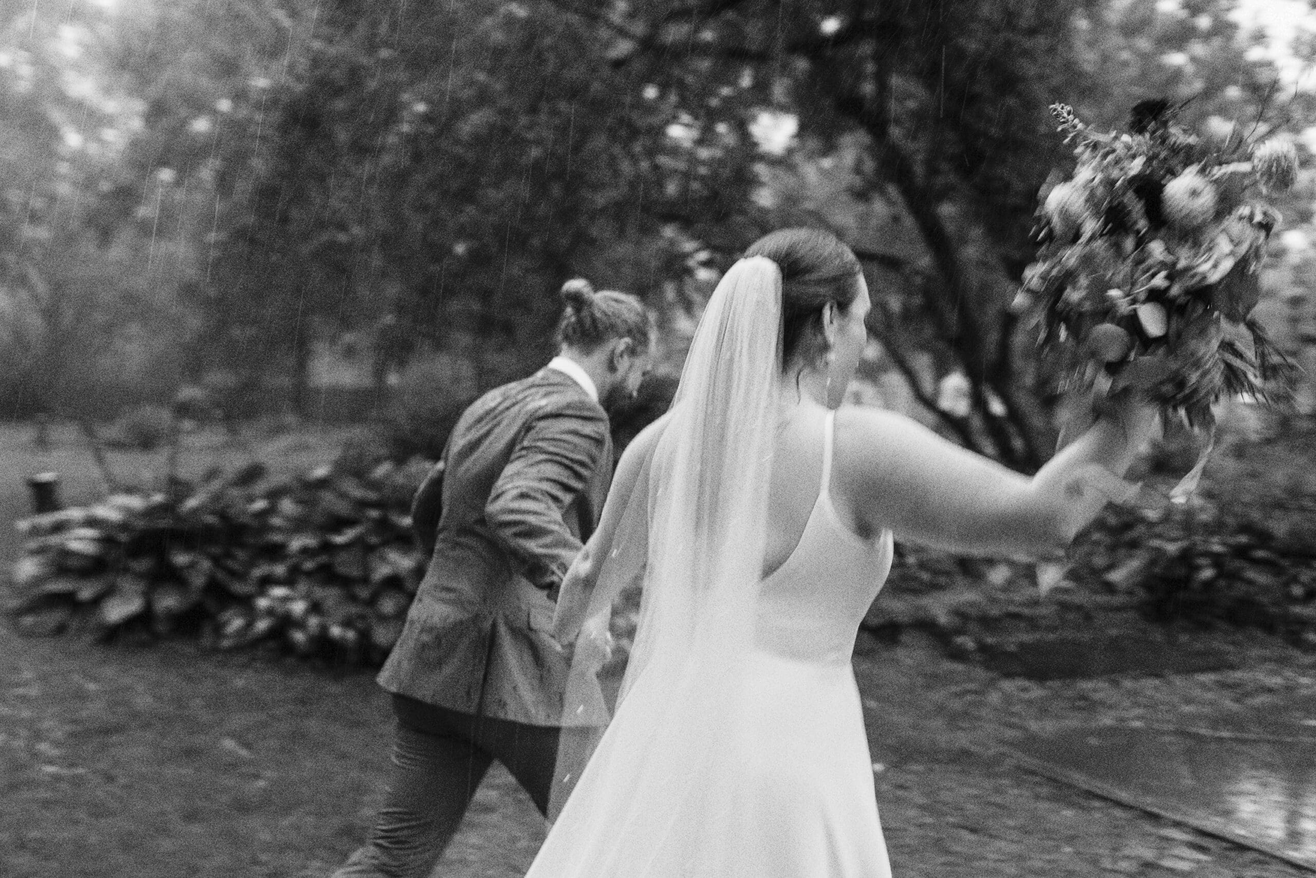 Bride and Groom running out of the rainy wedding ceremony holding hands at the Outing lodge in stillwater, MN. 
