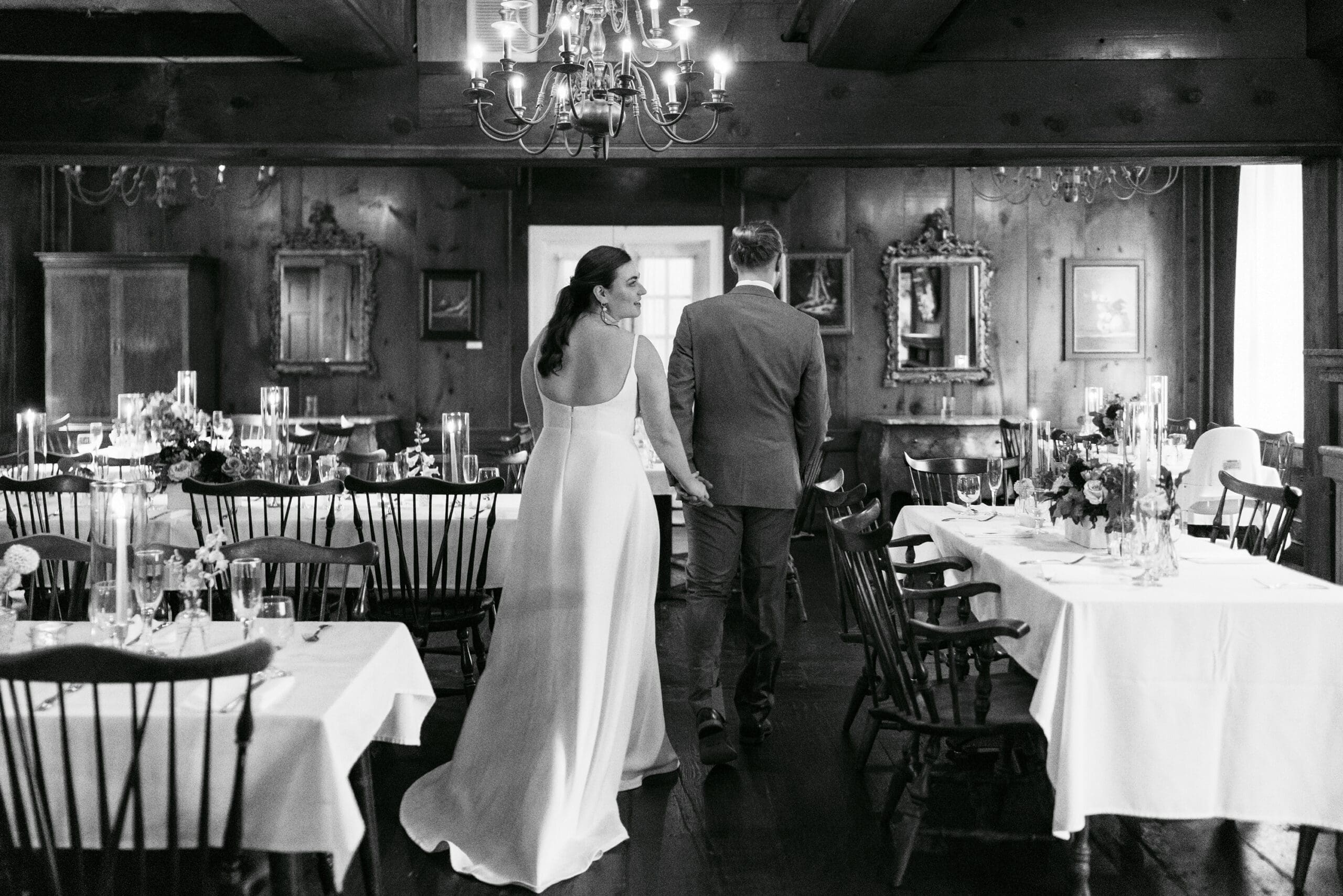 Bride and Groom walking through the reception to look at all the wedding details in The outing lodge.