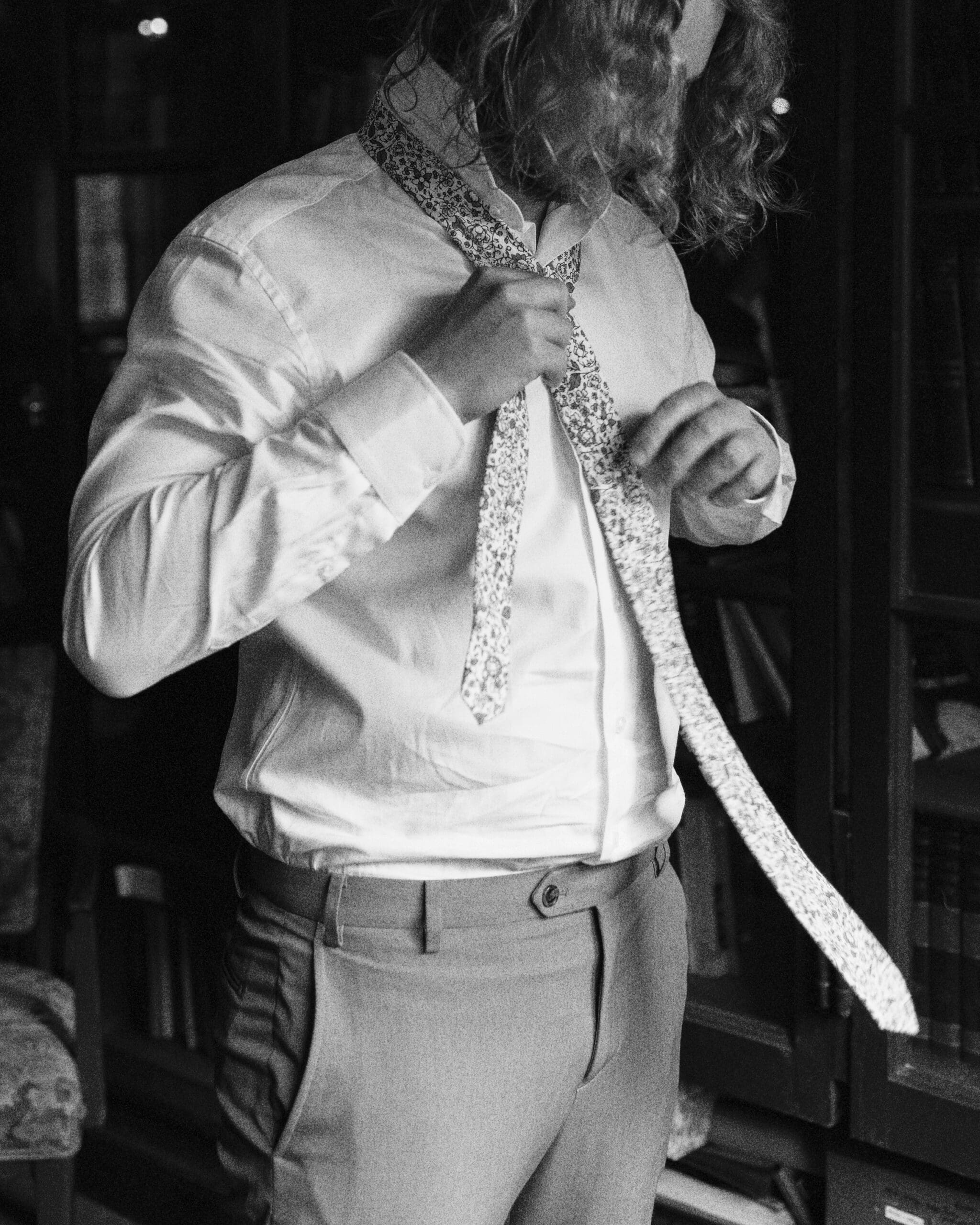 Groom tying wedding tie in the library at the Outing Lodge in Stillwater, MN. 
