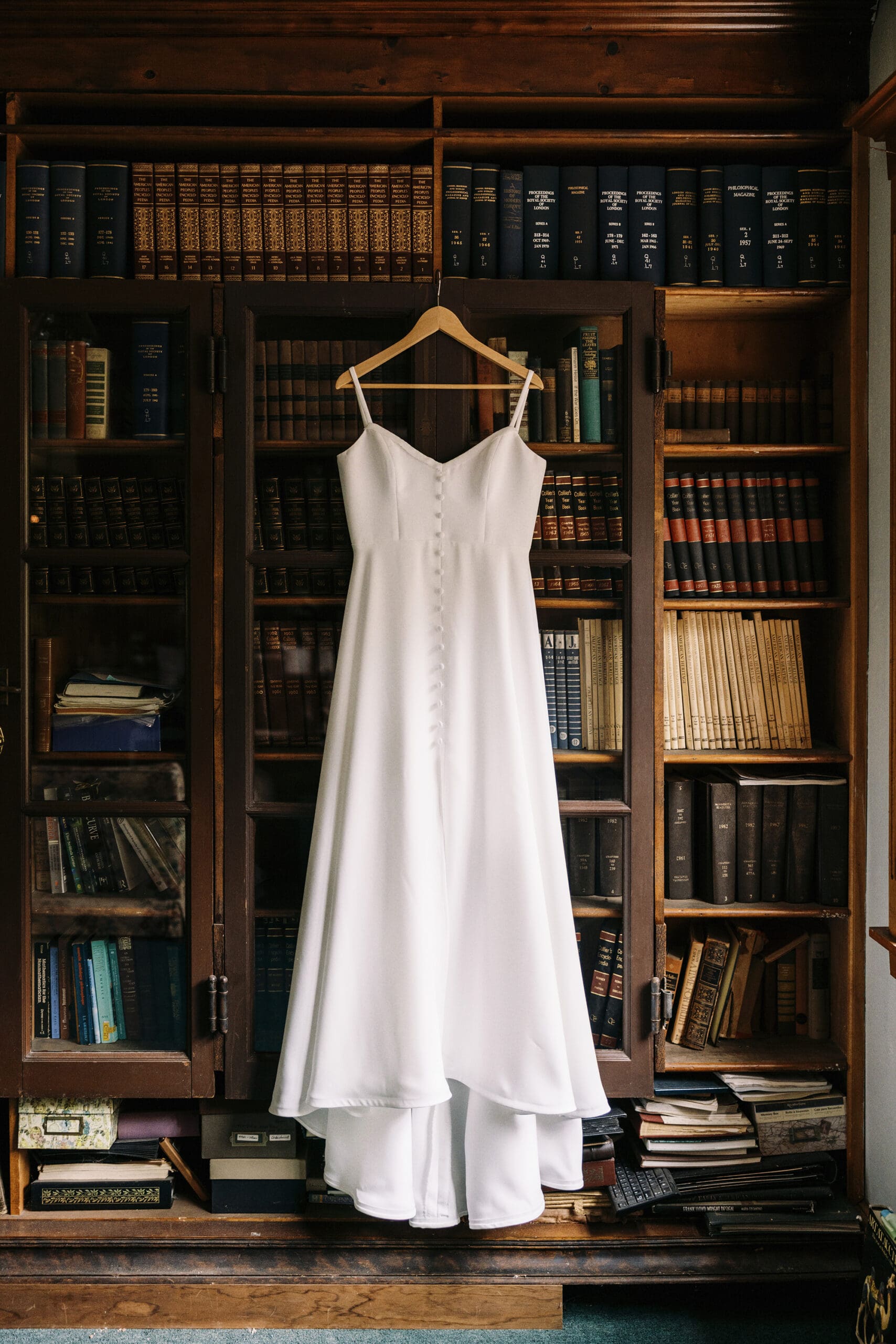 The Bride's dress hanging in the library at The outing Lodge wedding venue. 