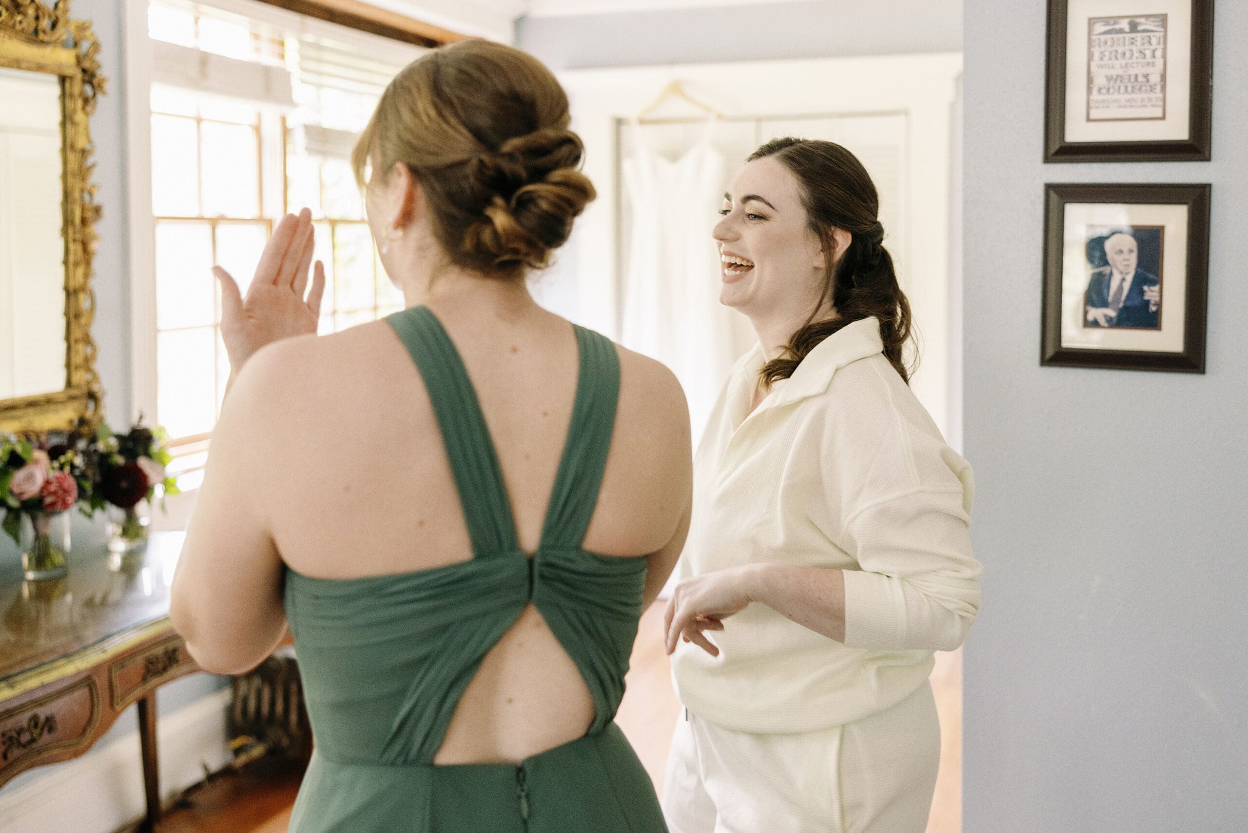 Bride laughing while getting ready in hotel room at The Outing lodge with her family. 
