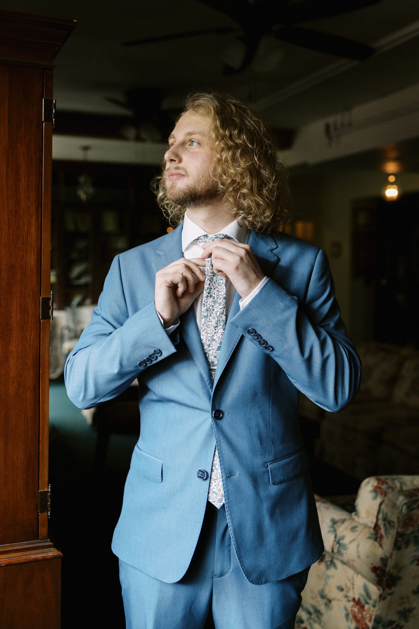 Portrait of the groom getting ready in the library at the Outing Lodge wedding venue. 